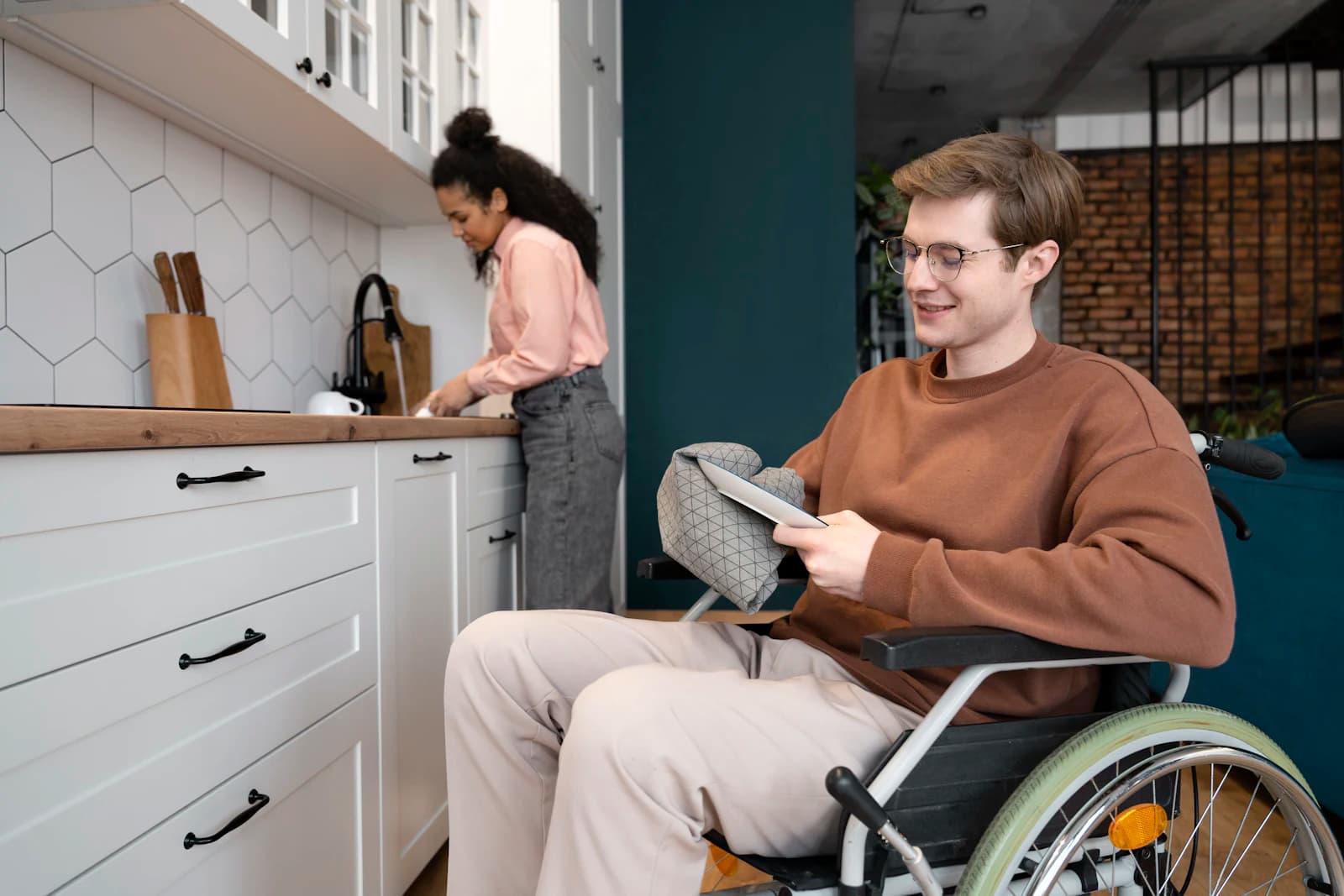 A young man who uses a wheelchair relaxing in his kitchen at home
